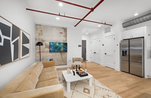 Old Town Alexandria Apartment | Design-forward flat in Old Town's most iconic building. Exposed brick, bold red ceiling pipes, corner bedroom bathed in natural light. Modern kitchen, quiet side street. Steps from 100+ restaurants & waterfront. A LovableBNB Collection listing.