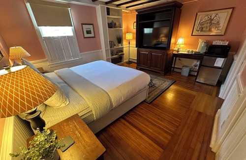 Newport Hotel | Step back in time with modern comfort in this charming exposed beam, private suite in Historic downtown Newport RI! King bed + pull-out sofa, ensuite bath, gas fireplace, AC, TV, mini fridge, coffee station. Steps to Thames Street, shops, wharfs